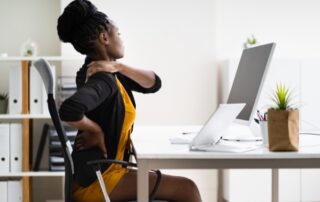 desk job pain - woman at desk with shoulder pain