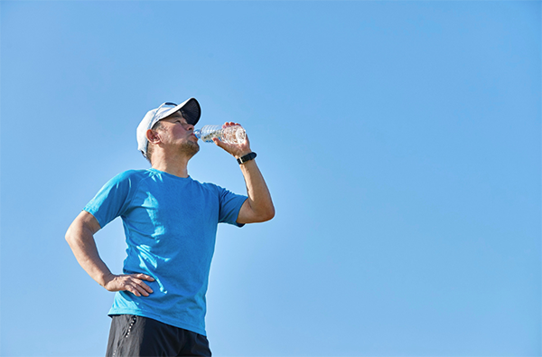 Man drinking to keep cool whilst exercising in heat.